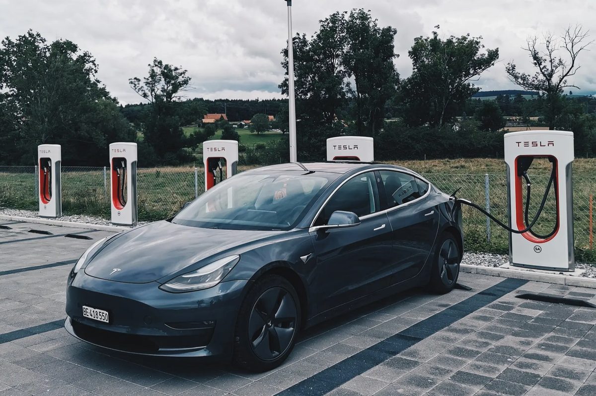 Tesla vehicles connected at a row of public charging stalls