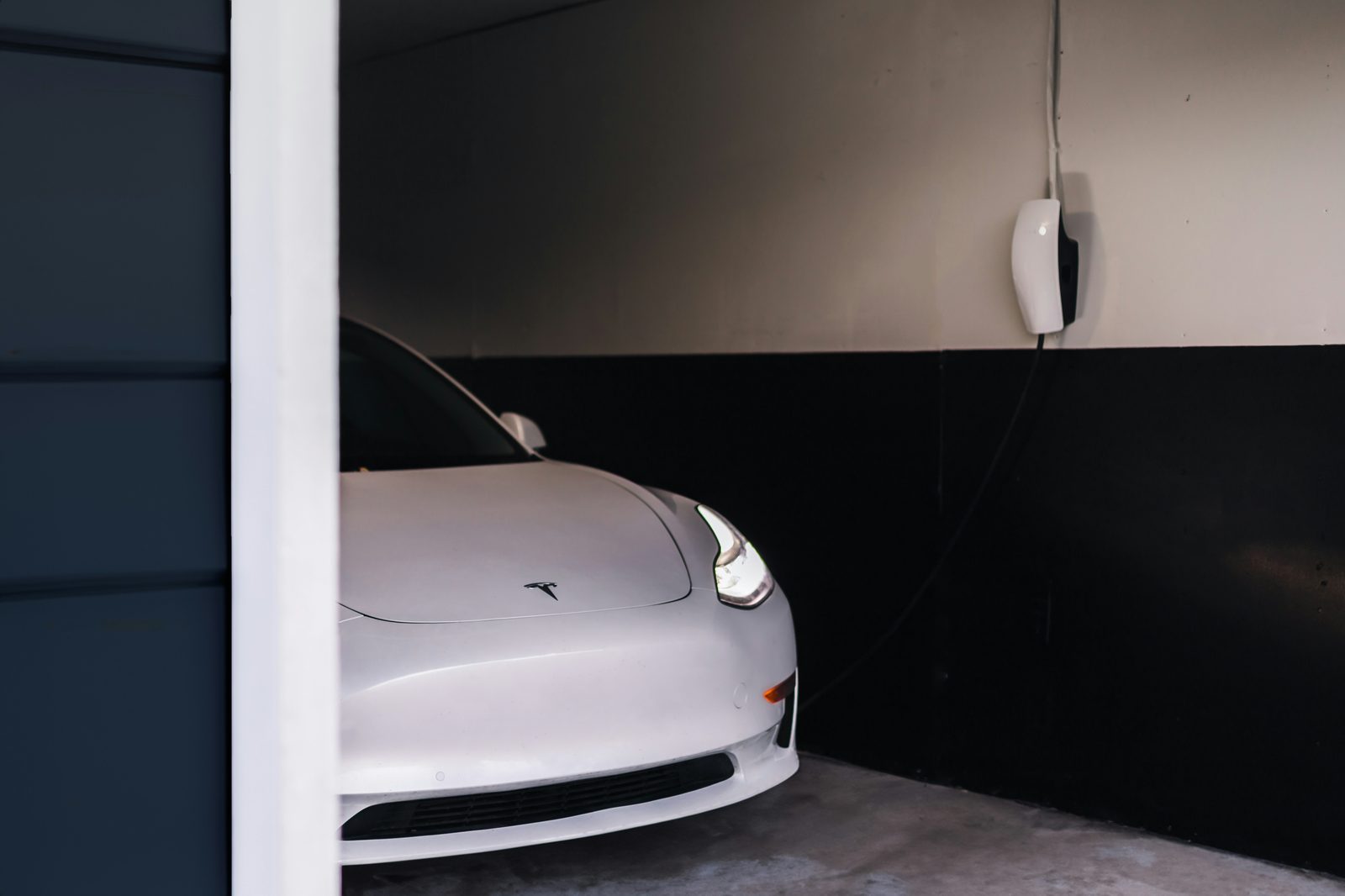 Wall-mounted Tesla charging unit with cable coiled on its holster